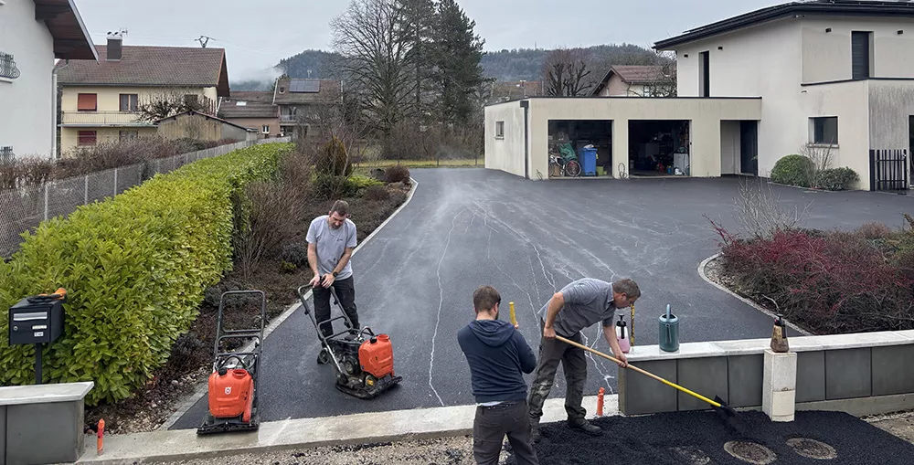 Ouvriers FCBE réalisant la pose et les finitions d'un enrobé pour une cour de maison dans le Jur