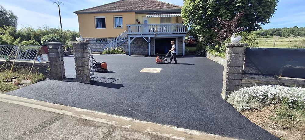 Aménagement d'une cour en enrobé noir devant une maison individuelle réalisé par FCBE dans le Jura